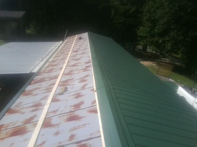 Old rusted panels beside newly installed green metal roofing — Wind Damage Roof Repair by Roofing Brothers in Birmingham