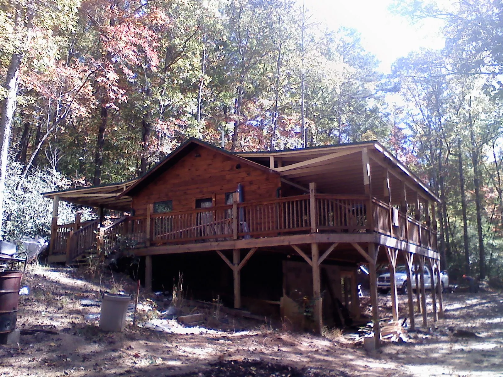 Log cabin with a wraparound porch and metal roof in the fall in Birmingham