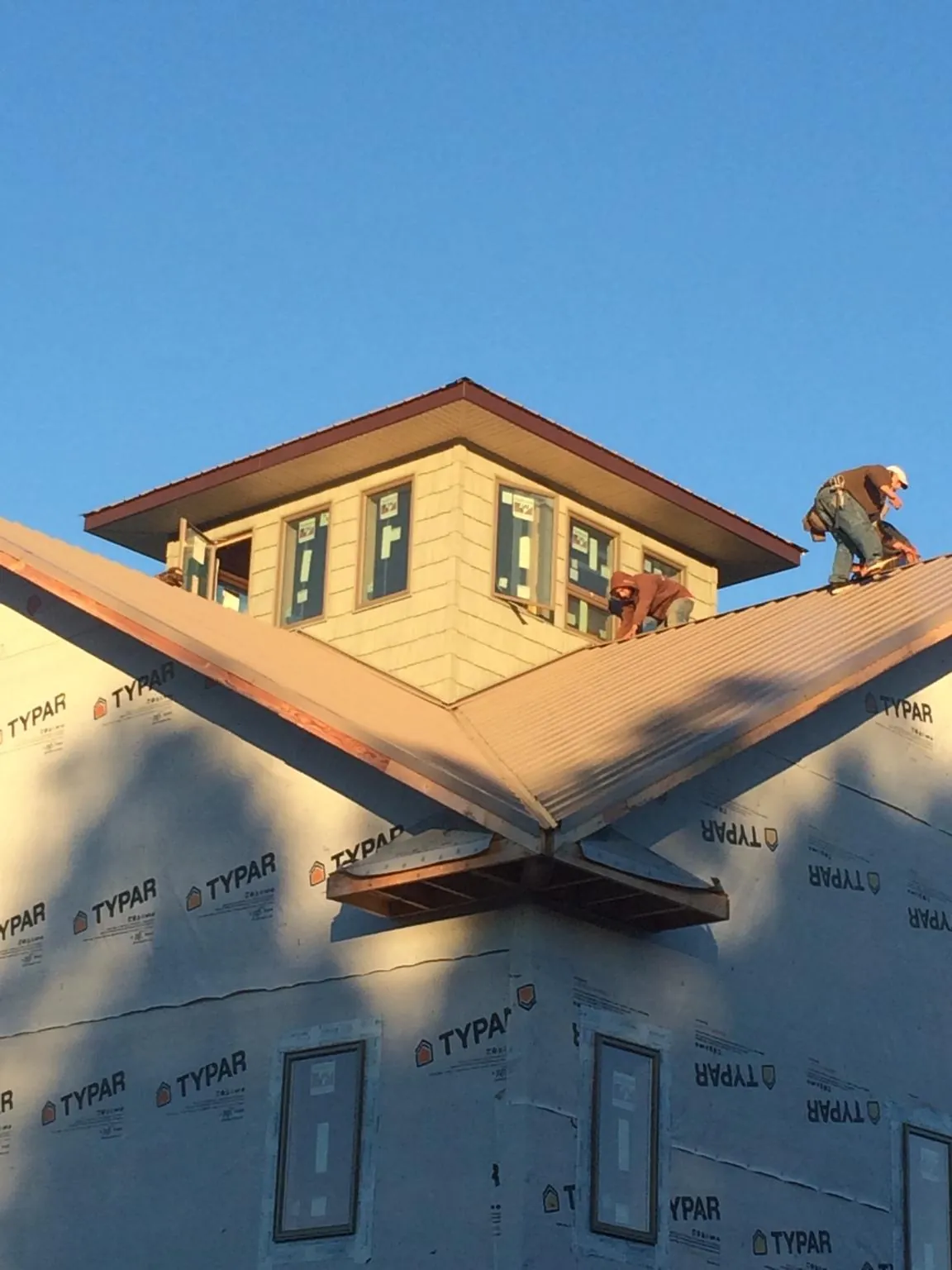Roofers working around a rooftop cupola on a new metal roof at sunset — Roof Waterproofing in Birmingham by Roofing Brothers